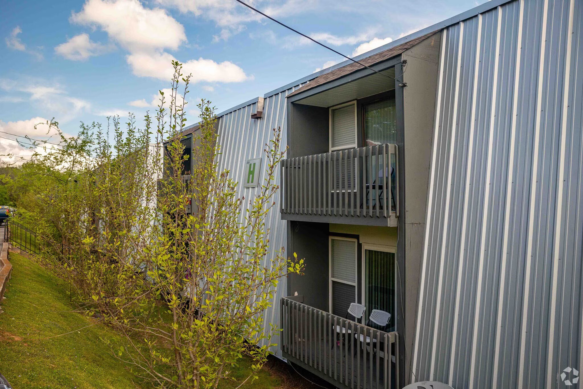 A building with a balcony and a small tree in front of it.